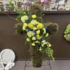 Moss-covered cross arrangement with yellow and white flowers