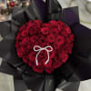 Heart-shaped bouquet of red roses with a pearl bow on black wrap