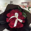 Bouquet of red roses wrapped in black paper with a white ribbon