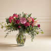 Vibrant pink and white carnations, lush greenery, and delicate accent flowers create