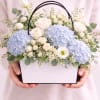 an airy garden- style arrangement featuring soft blue hydrangeas, creamy white roses