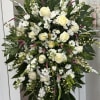 Large white floral standing spray with roses and daisies on an easel