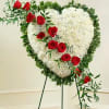 Heart-shaped white floral spray with red roses on a stand