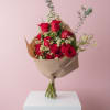 Bouquet of red roses and small white daisies wrapped in brown paper