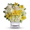 Yellow and white flower arrangement in a clear square vase