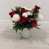 Red and white roses with white daisies in a clear glass vase