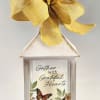 A white decorative lantern topped with a yellow fabric bow sets a