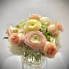 Pastel roses and ranunculus arranged in a clear glass vase
