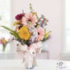Mixed gerbera daisy bouquet in a glass vase with a pink ribbon