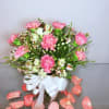 Pink carnations and white blooms in a vase with a white ribbon