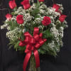Red roses and baby's breath in a glass vase with a red bow