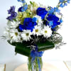 Blue roses and white daisies in a glass vase with ribbon
