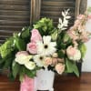 Pink roses and white daisies arranged in a white vase