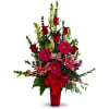 Tall bouquet of red roses, pink lilies, and gerbera daisies in a red vase