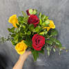 Red and yellow roses with glossy green foliage in a clear glass