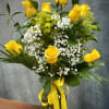 Yellow roses and white baby's breath in a glass vase with a yellow ribbon