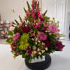 Layered pink and purple blooms rise in a tall, triangular silhouette designed