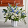 White and blue floral arrangement in a white vase