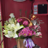 Basket arrangement of white lilies and pink daisies with a purple ribbon