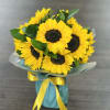 Bouquet of yellow sunflowers wrapped with blue paper and ribbon