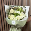 Bouquet of white and pale green flowers wrapped in green paper