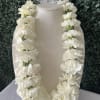White carnation lei draped over a beige display bust
