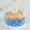Round floral cake with candles and peach roses on a white stand