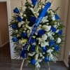 Large blue and white funeral spray on an easel with a ribbon