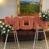 Pink floral letters on easels with white rose arrangements on both sides