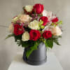 A striking cluster of red, pink and white roses arranged low and