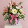 Pale pink roses and lilies mingle with creamy white gerbera daisies, chrysanthemums