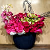 Pink roses and orchids arranged in a dark vase