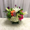 Mixed bouquet with lilies, tulips, roses, and hydrangea in a square vase