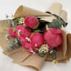 Bouquet of bright pink peonies with small white daisies in brown paper