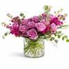 Pink roses and magenta flowers arranged in a clear glass vase