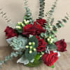 Red roses arranged with eucalyptus and a succulent in a green vase