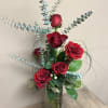 Red roses in a tall glass vase with eucalyptus stems