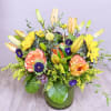 Mixed bouquet of lilies, roses, and yellow daisies in a glass vase