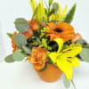 Orange and yellow bouquet with lilies, roses, and gerbera daisies in a vase