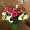 Pink and white roses with lilies in a green glass vase