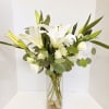 White lilies and roses in a tall glass vase
