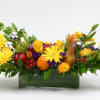 Yellow daisies and fruit arranged in a rectangular glass vase