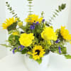 Yellow sunflowers and purple filler flowers in a white vase