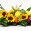 Low floral centerpiece with sunflowers and gourds in a rectangular container