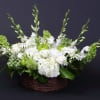White floral arrangement in a wicker basket with green apples