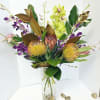 Tropical bouquet with orchids and protea in a clear glass vase