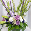 Purple and white flowers arranged in a glass vase