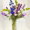 Tall vase arrangement with blue, purple, and pale pink flowers