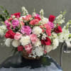 A lush, rounded basket overflowing with pink, red, and white blooms makes