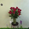 Red roses arranged in a clear glass vase on a small stand